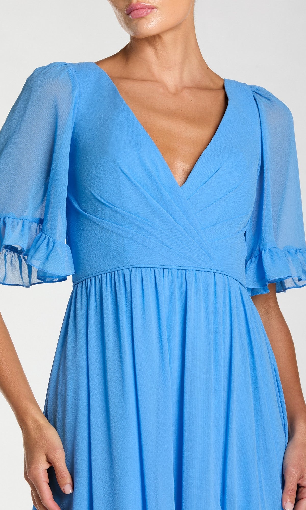 A woman wears the Long Formal Dress 55867 by Mac Duggal, featuring a light blue a-line silhouette, deep v-neckline, sheer ruffled sleeves, and a gathered waist.